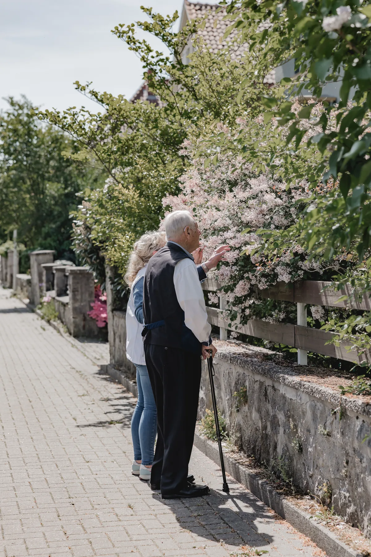 REKA Pflegekraft begleitet Senioren bei einem Spaziergang im blühenden Garten – Betreuung in Diekholzen